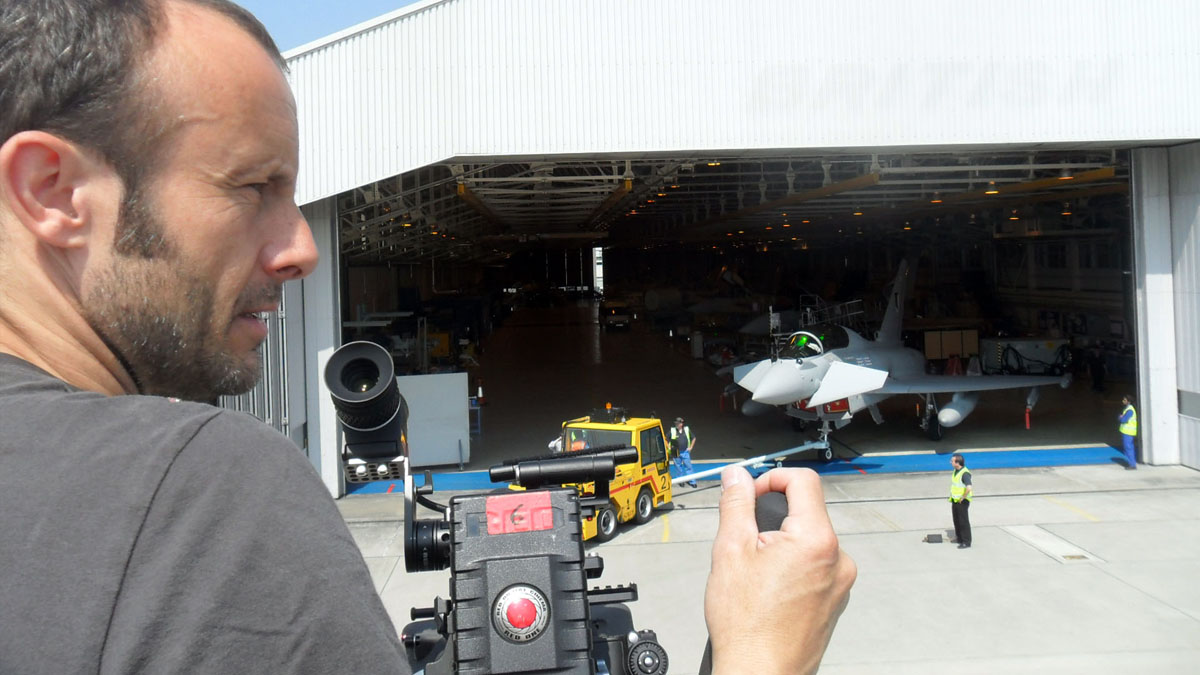 BAE Systems Cameraman Laurence Blyth on a platform films a Typhoon jet emerging from a hangar