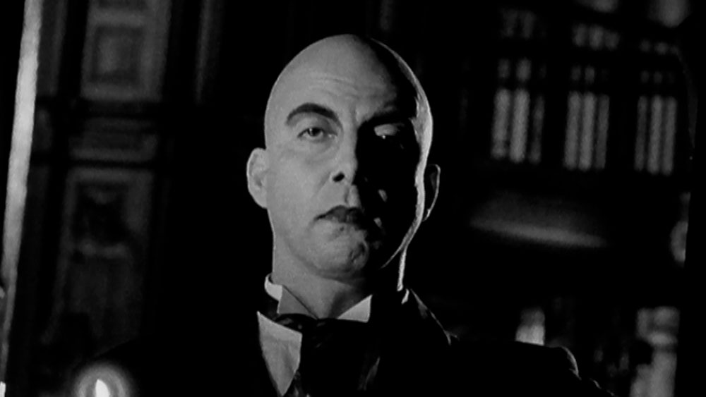 Opel Castle Vectra, video garage image, a dramatic bald butler holding a candelabra, in an open Castle doorway,  a grainy 16mm black and white image, experiential horror genre 